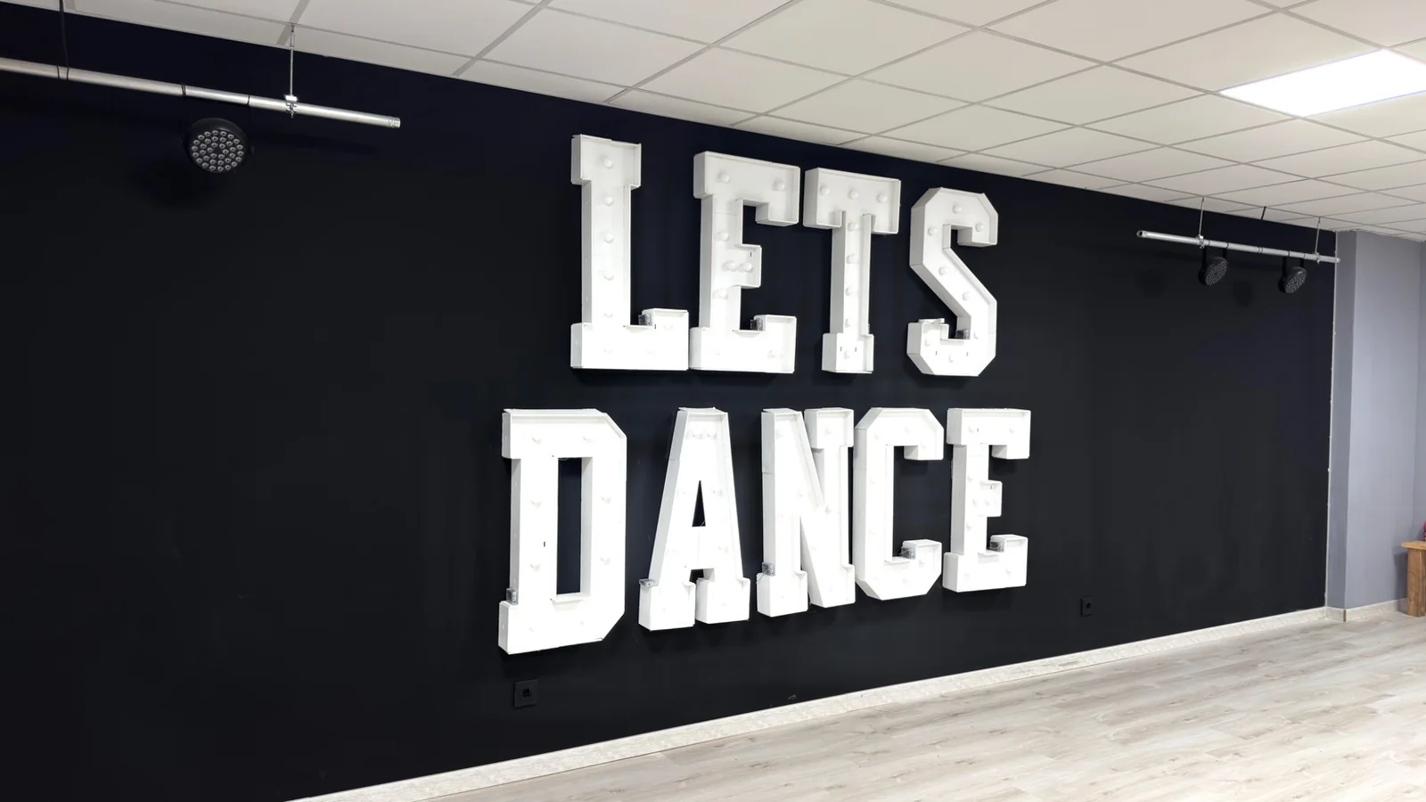 Rótulo luminoso LET'S DANCE en la pared de la academia